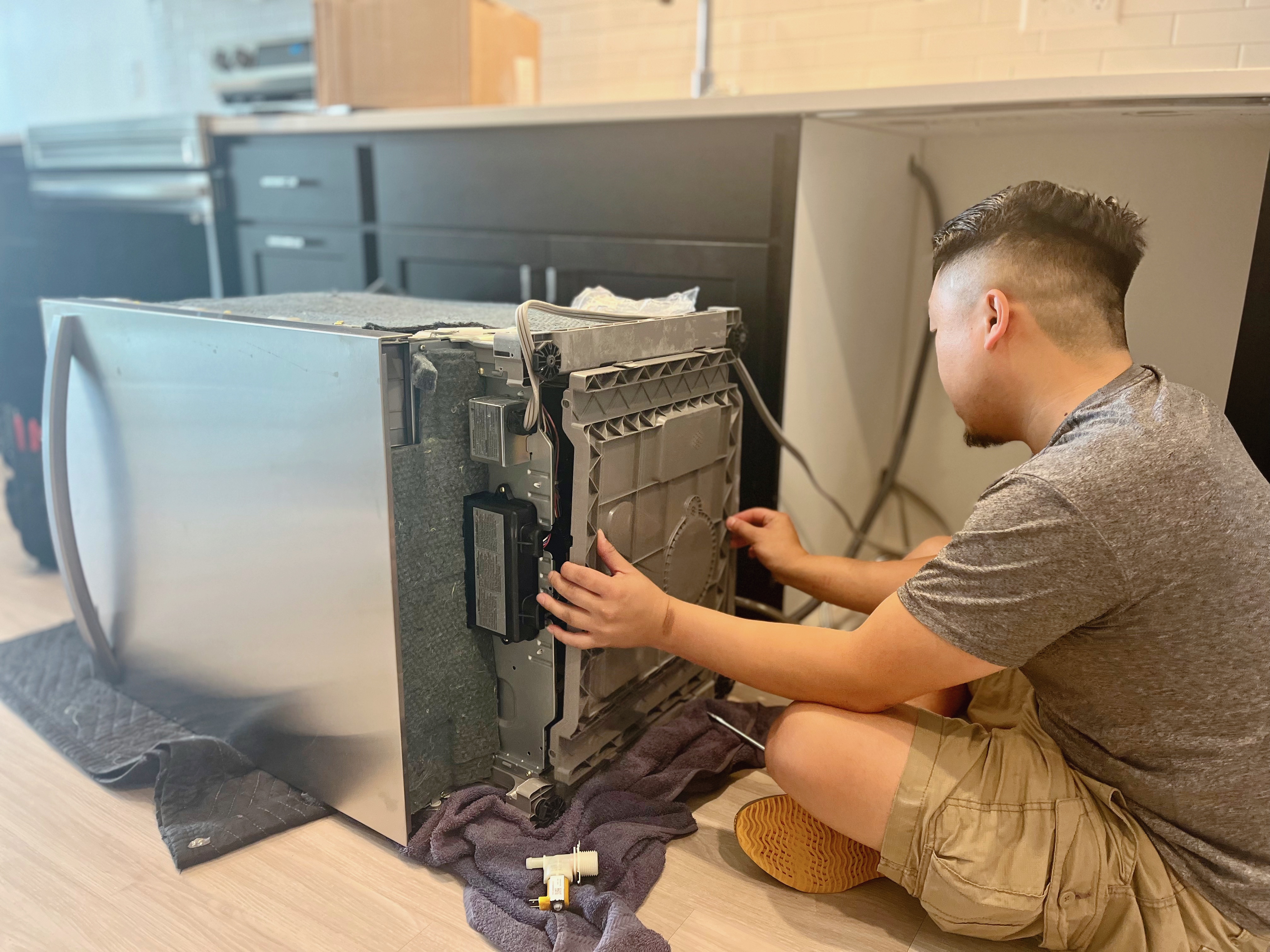 technicians repairs kitchen appliance at home